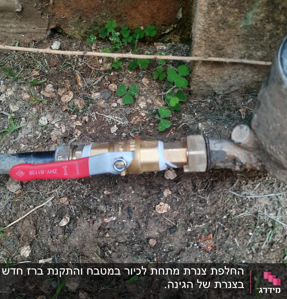 ברז מים עם ידית אדומה מחובר לצינור מתכת